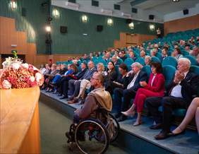 Pokaż zdjęcie: Na widowni kinoteatru siedzą ludzie. Wszyscy patrzą w kierunku sceny. Niektórzy biją brawo. 