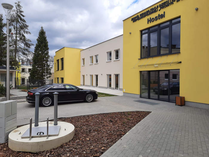 Pokaż zdjęcie: Elewacja budynku Promyka w Zielonej Górze, tuż przed budynkiem parking, stoi tam czarne auto typu Audi