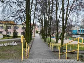 Widok pokazujący siedzibę OWIT-u w Bydgoszczy, usytuowany wśród drzew, widoczne podjazdy dla osób na wózkach inwalidzkich