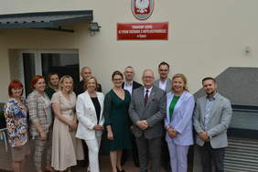 Pokaż zdjęcie: Pamiątkowa fotografia przed wejściem do budynku, grupa około 12 osób pozuje do zdjęcia