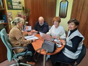 Pokaż zdjęcie: Trwają konsultacje dotyczące konkursu "Siła możliwości". Przy stole siedzą trzy kobiety i jeden mężczyzna. Rozmawiają ze sobą i uśmiechają się. Przed jedną z pań leży otwarty laptop. 