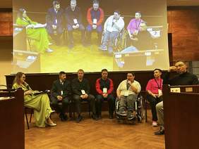 Panel dyskusyjny, widok z przodu, grupa 7 osób. Siedzą rozmawiają, z prawej strony tłumacz języka migowego