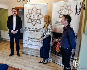 Pokaż zdjęcie: Dyrektor Oddziału Zach. PFRON ubrany w garnitur , obok Pani Joanna Czechowicz Kierownik SDS Choszczno, ubrana w jasną bluzkę i ciemne spodnie, z prawej strony Artur Groszkowski - Terapeuta w ciemnej koszuli i ciemnych spodniach. W tle baner z napisem SDS Choszczno.