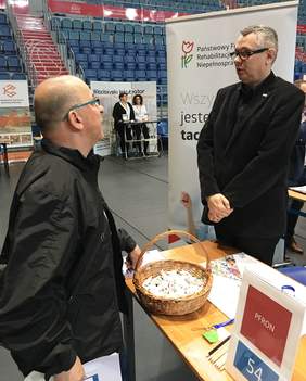 Przedstawiciel Kujawsko-Pomorskiego Oddziału PFRON - Piotr Kopyciński - rozmawia z odwiedzającym stoisko PFRON