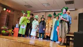 Pokaż zdjęcie: Grupa artystów w czapkach z pióropuszami w kolorze zielonym.