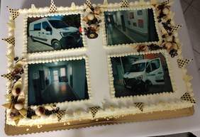 Pokaż zdjęcie: Duży tort na którym są 4 zdjęcia, dwa z nowymi busami i 2 z odnowionymi korytarzami jednej z placówek