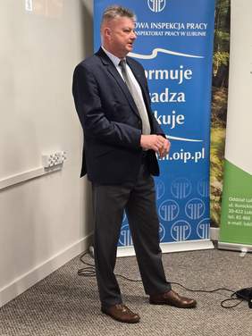 Pokaż zdjęcie: Mężczyzna w garniturze prowadzi wykład dla pracodawców.