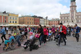 Pokaż zdjęcie: Bardzo liczba grupa dzieci na wózkach wraz z opiekunami ruszyła ze startu wyścigu na Rynku Wielkim w Zamościu