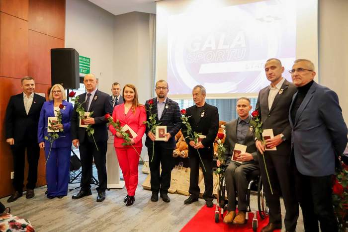 Pokaż zdjęcie: Sportowcy i działacze "Start Gorzów", ubrani odświętnie, stoją na tle prezentacji "Sportowe STARTy" i trzymają w rękach odznaczenia honorowe dla władz miasta Gorzów Wielkopolski