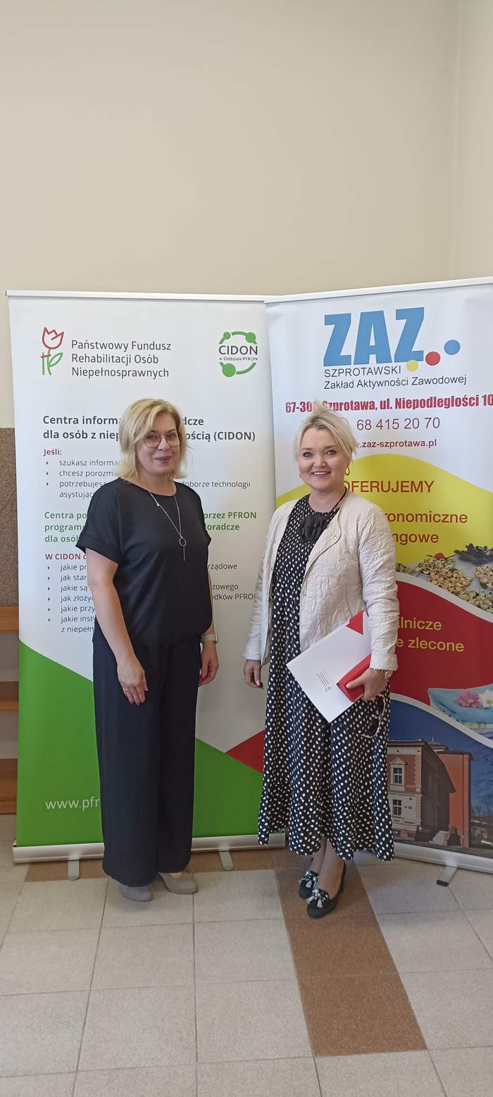 Pokaż zdjęcie: Dwie kobiety stoją obok siebie na tle banerów PFRON i ZAZ