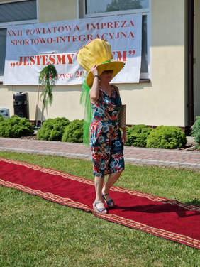 kobieta w sukience i dużym żółtym kapeluszu na czerwonym dywanie