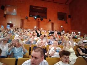 Pokaż zdjęcie: Na widowni Akademii Muzycznej siedzi tłum ludzi. Znajdują się wśród nich osoby z niepełnosprawnościami. Niektórzy biją brawo, a inni śpiewają. 