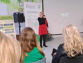 Na środku sali stoi Agnieszka Seweryniak, osoba niewidząca, która śpiewa dla zgromadzonych 