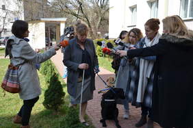 Pokaż zdjęcie: Kobieta, pies przewodnik na smyczy, zgromadzeni dziennikarze. 