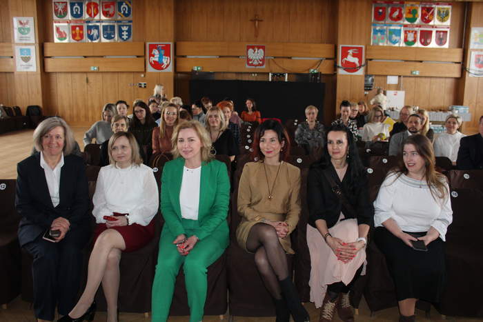 Pokaż zdjęcie: Zdjęcie osób siedzących w pierwszym rzędzie podczas konferencji, 6 kobiet.