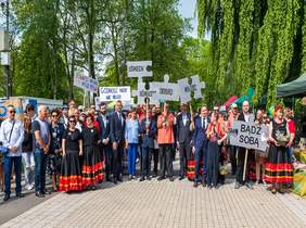 Pokaż zdjęcie: osoby stoją w parku trzymając w rekach transprenty z napisami - bądź sobą, dobro, uśmiech, równość, godność nigdy nie milczy, równość i wolność to nasze prawa 