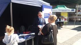 Pokaż zdjęcie: Dyrektor Oddziału Świętokrzyskiego PFRON Andrzej Michalski podczas udzielania informacji uczestnikowi plenerowych targów pracy