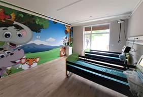 Sala w nowym budynku hospicjum - po lewo kolorowa ścian z bajkowymi postaciami, po prawo dwa łóżka specjalistyczne, na ścianie widać sprzęt medyczny