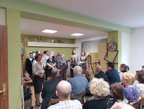 Pokaż zdjęcie: Zdjęcie uczestników Warsztatów Terapii Zajęciowej podczas występu przed zaproszonymi gośćmi.