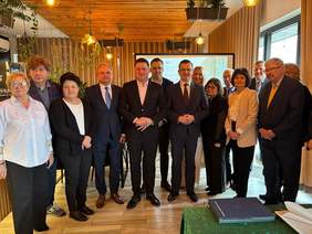 Pokaż zdjęcie: Do zdjęcia pozuje grupa kilkunastu osób. Są w niej kobiety i mężczyźni. Wszyscy są elegancko ubrani. 