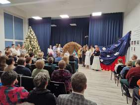 Widok na zebranych zza ich pleców, z przodu widać szopkę i aktorów uczestniczących w przedstawieniu