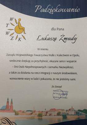 Pokaż zdjęcie: Dyplom z podziękowaniem. W treści dyplomu: Podziękowanie dla Łukasza Żmudy. W imieniu Wojewódzkiego Towarzystwa Walki z Kalectwem  w Opolu, serdecznie dziękuję za przychylność, okazane serce i wsparcie - Dni Osób Niepełnosprawnych i Jarmarku N