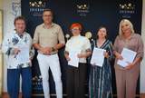 Do zdjęcia pozuje mężczyzna i cztery kobiety. Panie prezentują podpisane umowy. W tle widać baner powiatu zgierskiego. 