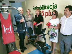 Pokaż zdjęcie: Pięć osób ogląda pomieszczenie siłowni w ośrodku