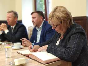 Pokaż zdjęcie: Dyrektor Marta Mordarska wpisuje się do księgi pamiątkowej
