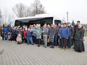 Pokaż zdjęcie: Uczestnicy WTZ, kadra oraz zaproszeni goście stoją na tle białego, nowego pojazdu.