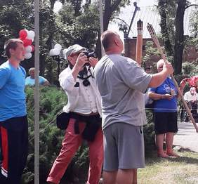 Pokaż zdjęcie: Mężczyzna trzymający w ręku pochodnię, którą podpala stojący obok znicz olimpijski