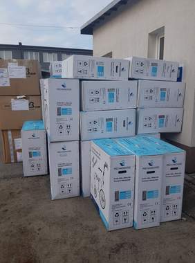 Pokaż zdjęcie: na zdjęciu miejsce przed budynkiem Oddziału Podkarpackiego PFRON w Rzeszowie,na placu stoją pudełka z zapakowanym towarem w którym znajdują się nowe wózki inwalidzkie na opakowaniu rysunek modelu wózka oraz kartony ze śpiworami i kocami