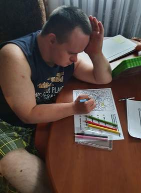 Pokaż zdjęcie: Uczestnik WTZ w domu wykonuje prace zlecone przez terapeutę - rozwiązuje i koloruje łamigłówki