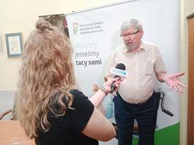 Dyrektor Łódzkiego Oddziału PFRON udziela wywiadu dziennikarce telewizji TOYA. Widać także fragment kamery. W tle widać równieź baner Łódzkiego Oddziału PFRON. 