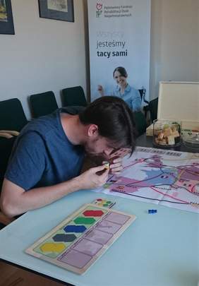 Pokaż zdjęcie: Mateusz Krzyszkowski testujący grę planszową w siedzibie Oddziału Małopolskiego