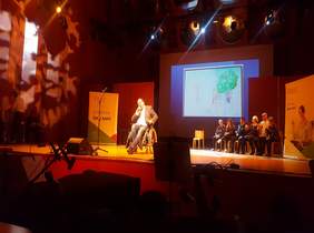 Pokaż zdjęcie: na zdjęciu scena Akademii Muzycznej na której śpiewa chłopak który siedzi na wózku i trzyma mikrofon