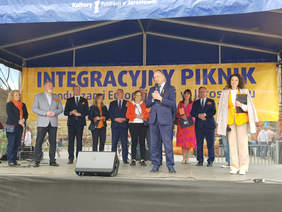 na scenie w rynku stoją w rzędzie ludzie, mężczyzna przemawia