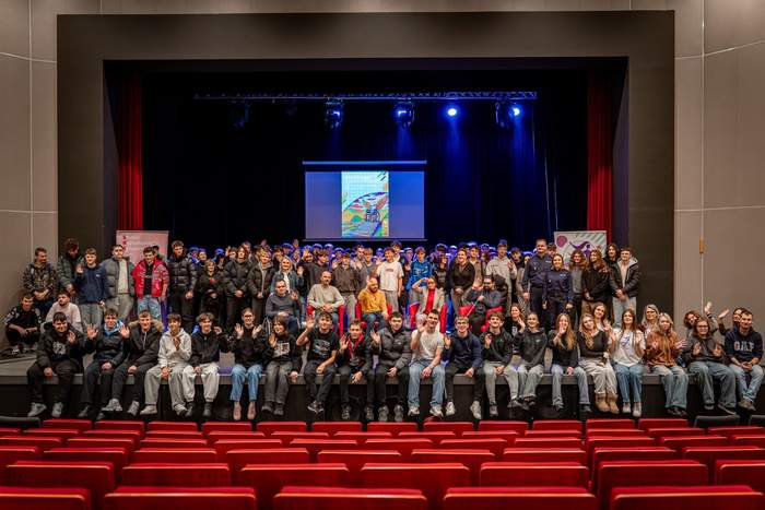 Pokaż zdjęcie: W nowoczesnej sali kinowej znajdują się uczestnicy spotkania ustawieni do zdjęcia grupowego