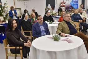 Pokaż zdjęcie: Zdjęcie sali, przy okrągłych stolikach siedzą osoby zaproszone na X wieczór dobroczynności 