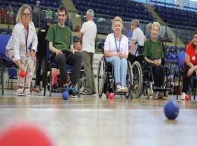 Pokaż zdjęcie: na zdjęciu uczestnicy Spartakiady, jedna z zawodniczek rzuca czerwoną kulę, rywalizacja drużynowa