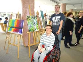 Pokaż zdjęcie: Uczestnicy wystawy na tle prac