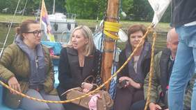 Pokaż zdjęcie: W łódce z żaglem w kapokach siedzą cztery osoby.