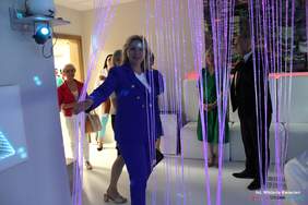 Pokaż zdjęcie: Kobieta blondynka w niebieskim garniturze ogląda pomieszczenie, salę doświadczeń