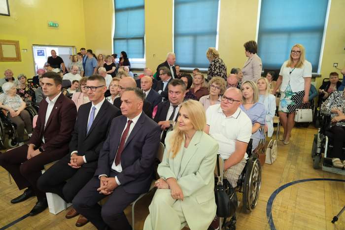 Pokaż zdjęcie: Goście zaproszeni na uroczystość jubileuszu siedzą na krzesełkach.