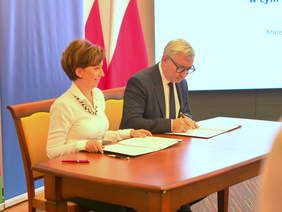 Pokaż zdjęcie: Dwie osoby podpisują dokumenty.