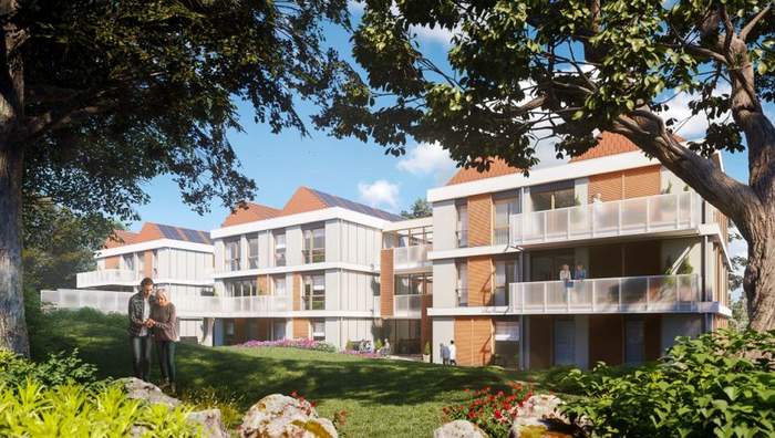 Mężczyzna prowadzi starszą kobietę pod ręką po trawie. Za nimi dwupiętrowe budynki szklanymi balkonami. Na pierwszym planie drzewa i krzewy.