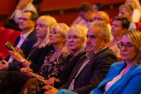 Kobiety i mężczyźni siedzą na fotelach na widowni