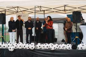 Scena plenerowa. Na scenie stoją kobiet i mężczyźni elegancko ubrani, przemawiają do mikrofonu.