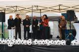 Scena plenerowa. Na scenie stoją kobiet i mężczyźni elegancko ubrani, przemawiają do mikrofonu.