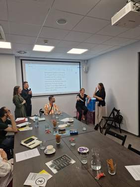 Pokaż zdjęcie: Grupa osób uczestniczy w warsztacie. Toczy się dyskusja.